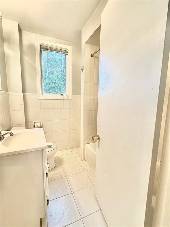 124 Grant Ave, Medford, MA 02155 - bathroom featuring tile patterned floors, toilet, washtub / shower combination, vanity, and tile walls