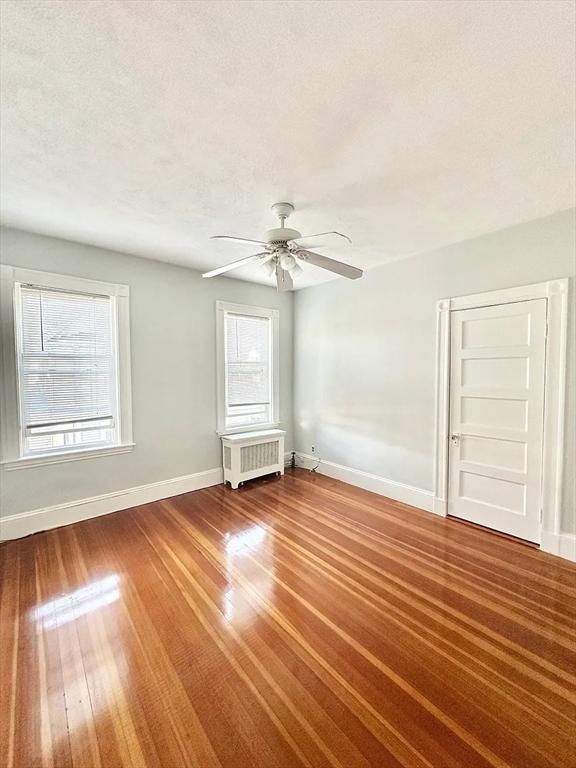 124 Grant Ave, Medford, MA 02155 - empty room with radiator heating unit, baseboards, ceiling fan, and wood finished floors