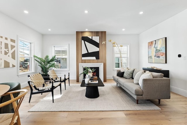 living room with a fireplace, light wood-type flooring, and plenty of natural light