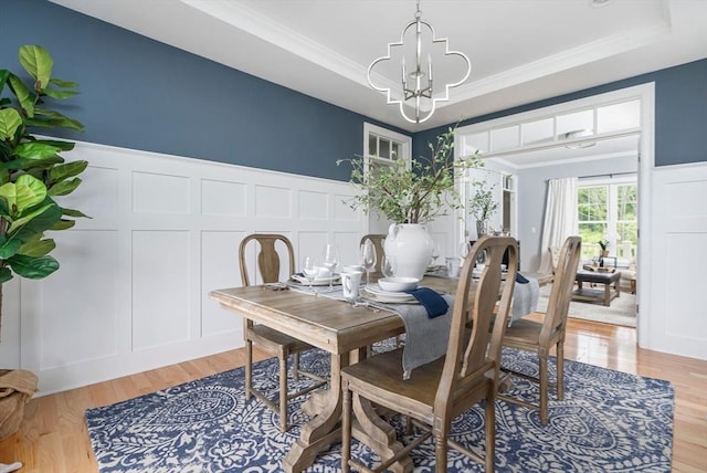 dining room featuring an inviting chandelier, a tray ceiling, light hardwood / wood-style flooring, and crown molding