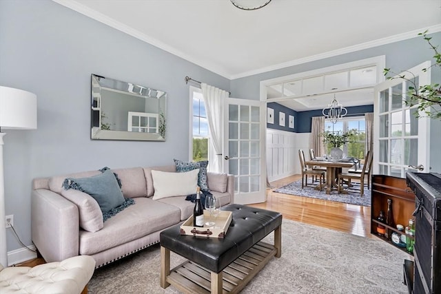 living room featuring crown molding, plenty of natural light, hardwood / wood-style floors, and a chandelier