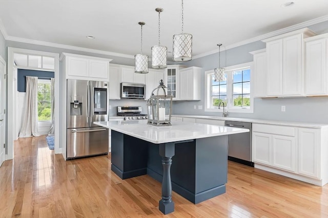 kitchen with a kitchen island, appliances with stainless steel finishes, white cabinets, crown molding, and light hardwood / wood-style flooring