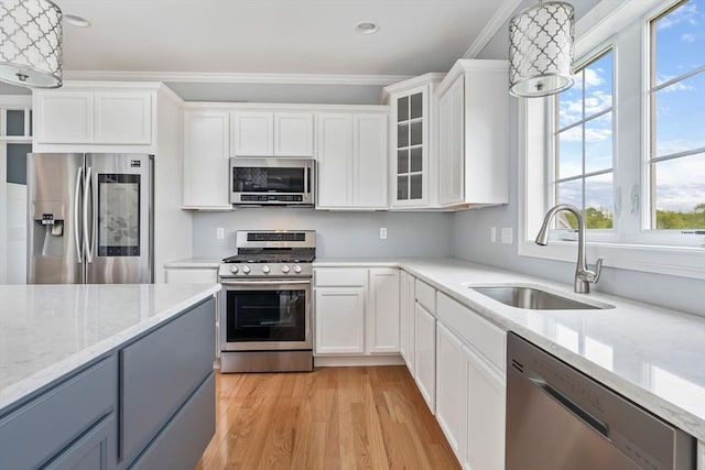 kitchen featuring sink, white cabinetry, decorative light fixtures, light hardwood / wood-style flooring, and appliances with stainless steel finishes