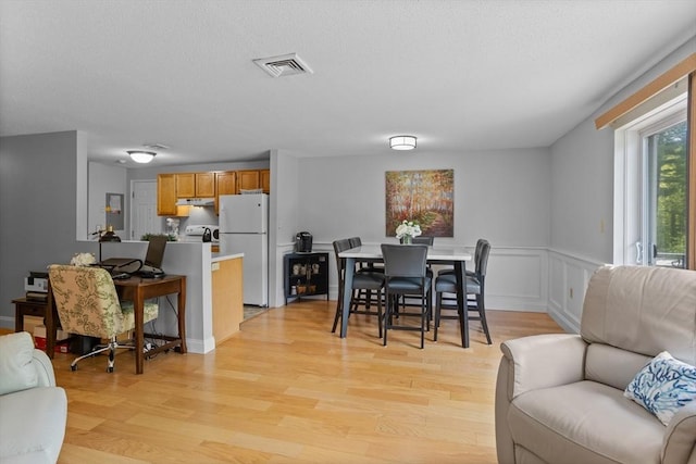 181 Littleton Rd Unit 333, Chelmsford, MA 01824 - dining area featuring light wood finished floors, a wainscoted wall, and a textured ceiling