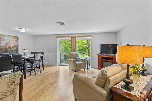 181 Littleton Rd Unit 333, Chelmsford, MA 01824 - living room with wood finished floors, a textured ceiling, a decorative wall, and wainscoting
