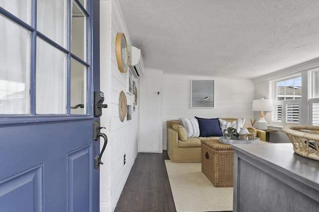 living area featuring wood finished floors, a textured ceiling, and a wall unit AC