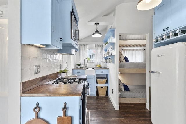 kitchen featuring stainless steel appliances, dark wood-style flooring, blue cabinetry, backsplash, and wooden counters