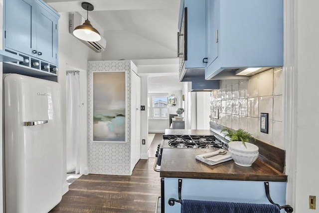 kitchen featuring refrigerator, blue cabinets, dark wood-style flooring, dark countertops, and lofted ceiling