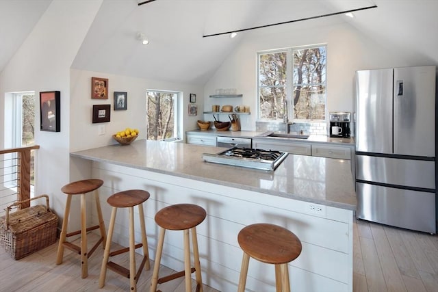 kitchen featuring lofted ceiling, sink, appliances with stainless steel finishes, a kitchen breakfast bar, and kitchen peninsula