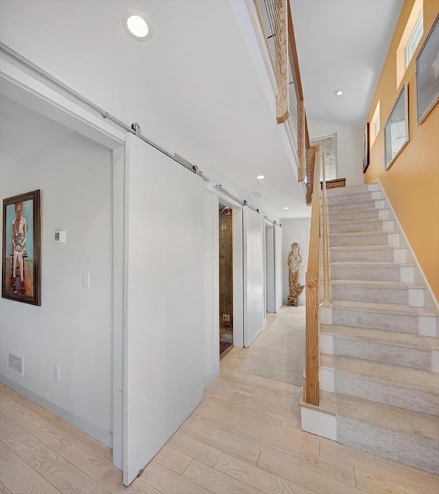 hall featuring a barn door and light hardwood / wood-style floors