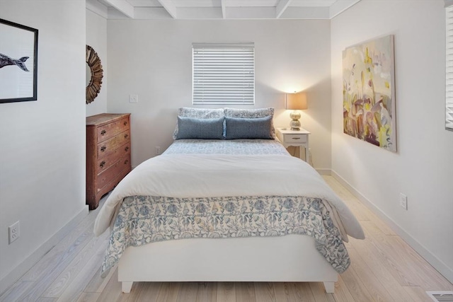 bedroom featuring beam ceiling and light hardwood / wood-style floors