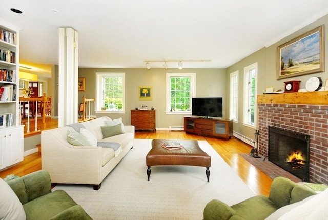 1074 Concord Rd, Sudbury, MA 01776 - living room featuring wood finished floors, a brick fireplace, baseboard heating, and baseboards