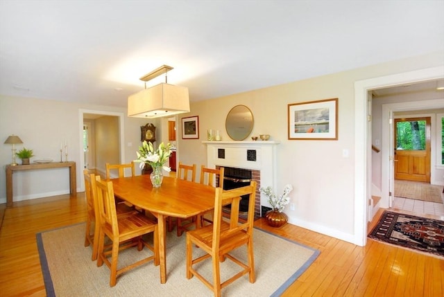 1074 Concord Rd, Sudbury, MA 01776 - dining area with light wood-type flooring, baseboards, and a brick fireplace