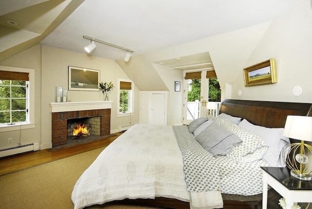 1074 Concord Rd, Sudbury, MA 01776 - bedroom with a baseboard radiator, multiple windows, rail lighting, a brick fireplace, and vaulted ceiling