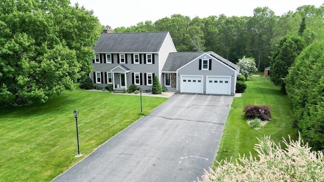 16 Blueberry Way, Webster, MA 01570 - colonial-style house featuring a garage, asphalt driveway, a chimney, and a front lawn