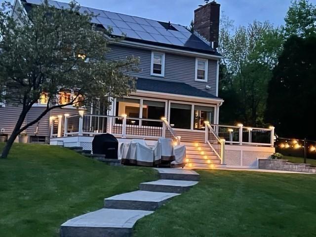 16 Blueberry Way, Webster, MA 01570 - back of house featuring a chimney, roof mounted solar panels, a lawn, and a wooden deck