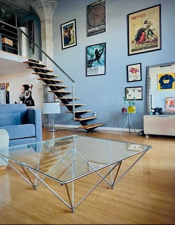 stairs featuring wood finished floors, baseboards, and a towering ceiling