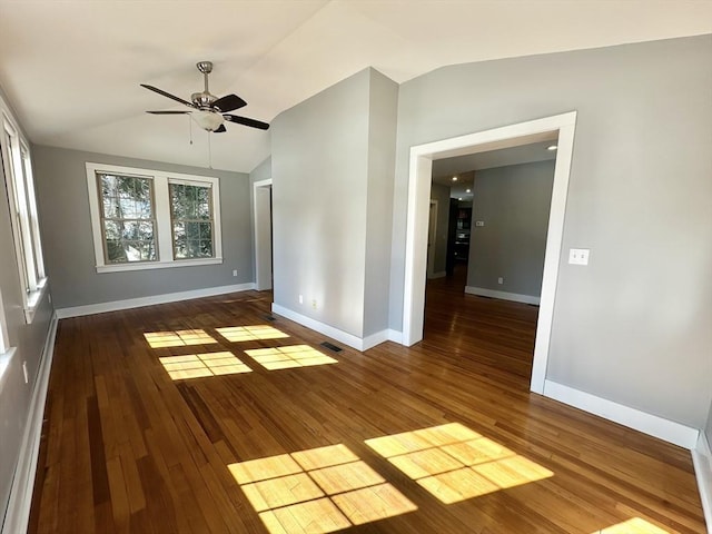 unfurnished room featuring visible vents, vaulted ceiling, baseboards, and wood finished floors