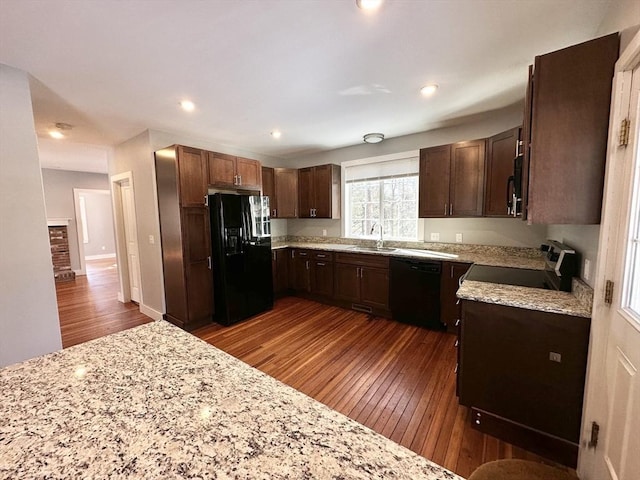 kitchen featuring light stone counters, recessed lighting, a sink, dark wood-style floors, and black appliances