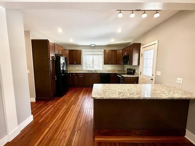 kitchen featuring a peninsula, black appliances, dark wood finished floors, and a wealth of natural light