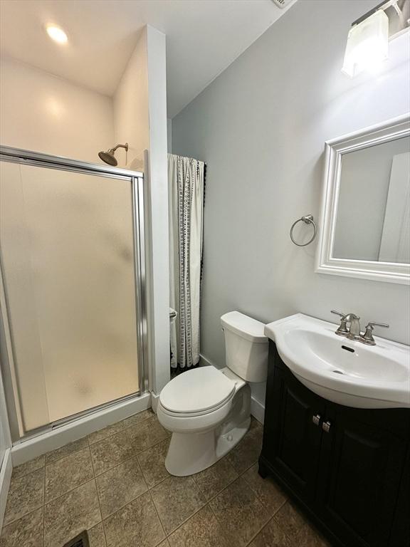 full bathroom featuring vanity, a shower stall, and toilet