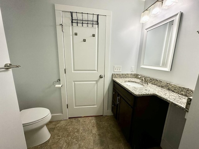 bathroom featuring baseboards, vanity, and toilet