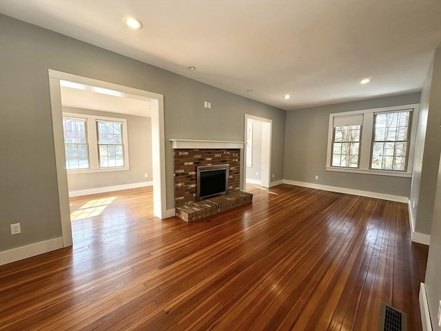 unfurnished living room with dark wood-style floors, a fireplace, visible vents, and baseboards