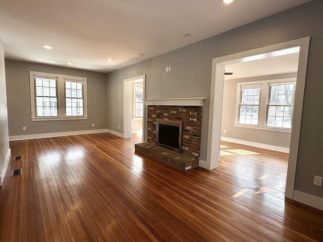 unfurnished living room with baseboards, a fireplace, plenty of natural light, and hardwood / wood-style floors