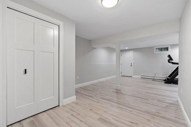 basement featuring a baseboard heating unit and light hardwood / wood-style flooring