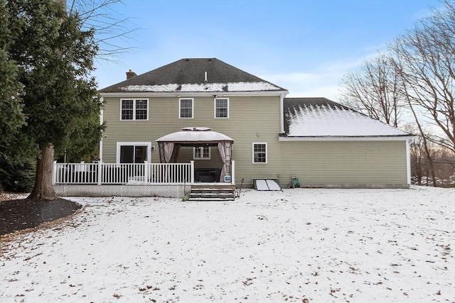 snow covered back of property featuring a deck and a gazebo