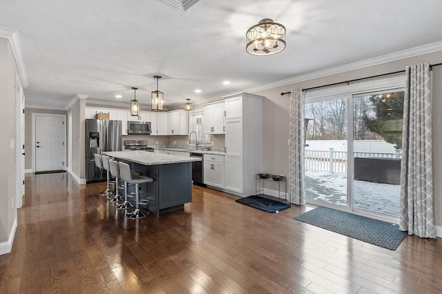 kitchen featuring pendant lighting, a kitchen island, white cabinetry, a breakfast bar area, and stainless steel appliances