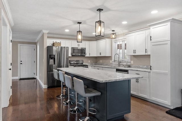 kitchen with white cabinetry, hanging light fixtures, stainless steel appliances, and a kitchen island