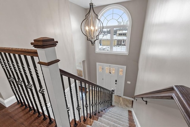 stairway featuring hardwood / wood-style flooring, a towering ceiling, and a chandelier