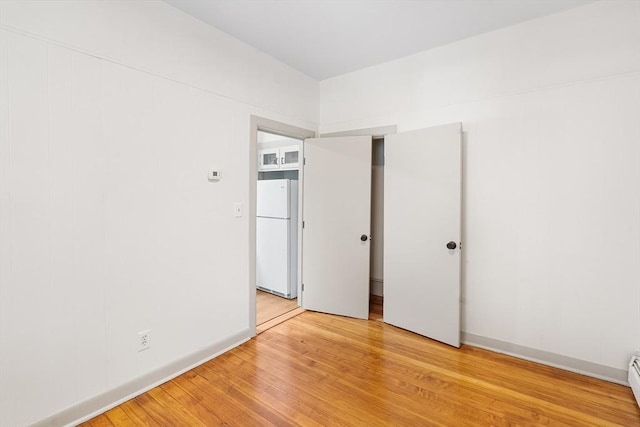 31 Hunting St, Cambridge, MA 02141 - unfurnished bedroom with freestanding refrigerator, light wood-type flooring, and baseboard heating