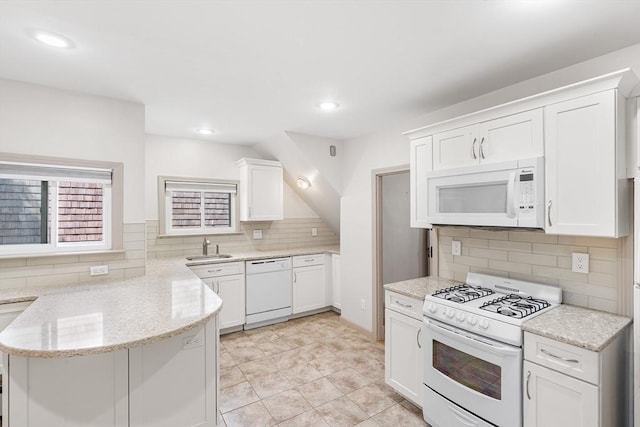 31 Hunting St, Cambridge, MA 02141 - kitchen featuring white appliances, a peninsula, white cabinetry, tasteful backsplash, and light stone counters