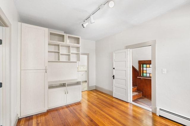 31 Hunting St, Cambridge, MA 02141 - unfurnished room featuring a baseboard heating unit, light wood-type flooring, stairway, and rail lighting