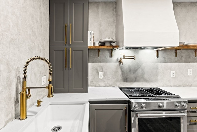 kitchen with gray cabinets, high end stainless steel range oven, sink, and light stone countertops