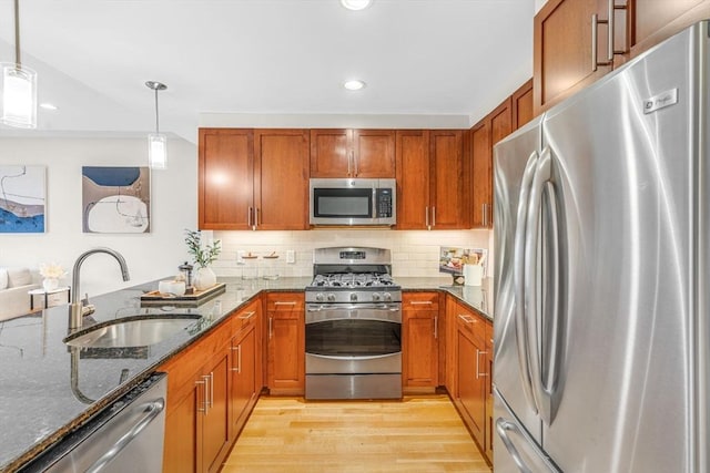 321 Hammond Pond Pkwy Unit 103, Brookline, MA 02467 - kitchen featuring stainless steel appliances, a sink, light wood finished floors, dark stone counters, and brown cabinetry