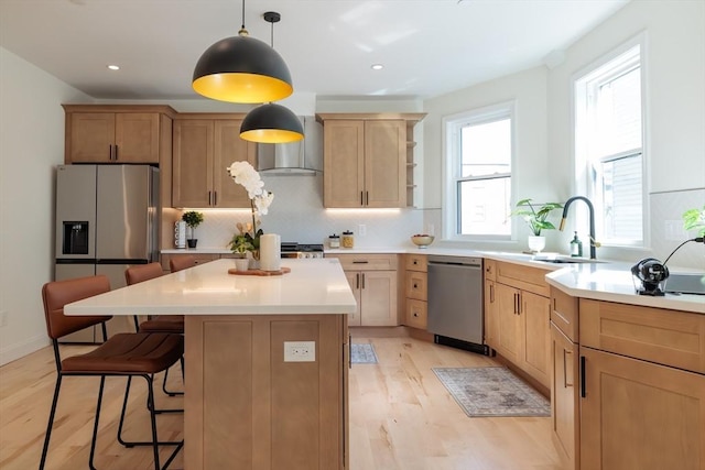 59 Dartmouth St Unit A, Somerville, MA 02145 - kitchen featuring appliances with stainless steel finishes, decorative backsplash, light wood-style flooring, a breakfast bar, and pendant lighting