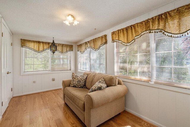 sitting room with a textured ceiling, baseboards, and light wood-style flooring