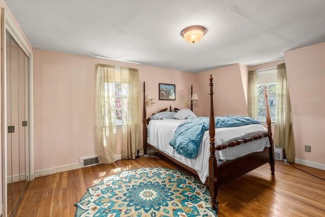 bedroom with baseboards, wood finished floors, and visible vents