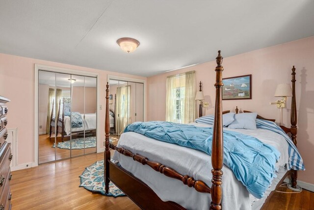 bedroom with light wood-type flooring, baseboards, and two closets