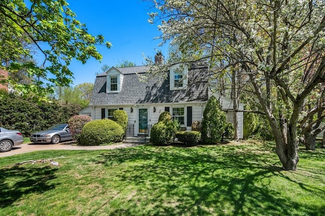 view of front of house with roof with shingles, a front yard, and a chimney