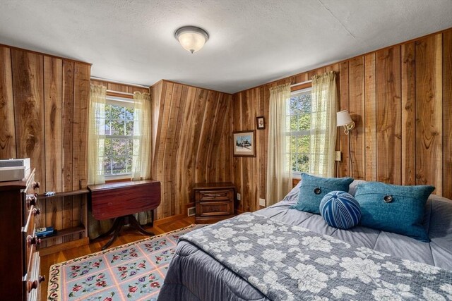bedroom featuring multiple windows, wood walls, and wood finished floors