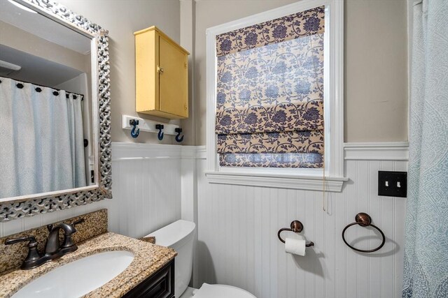 bathroom featuring a wainscoted wall, vanity, and toilet
