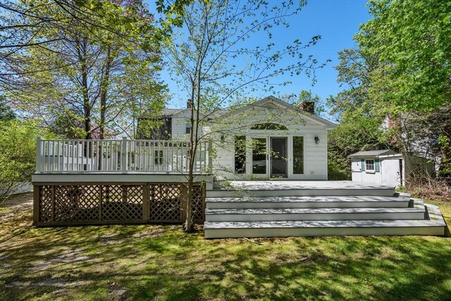 back of property with an outdoor structure, a chimney, a shed, and a deck