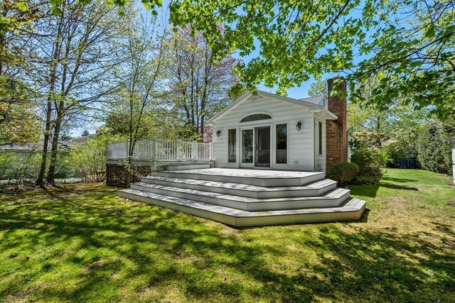 rear view of property featuring a yard, a deck, and a chimney