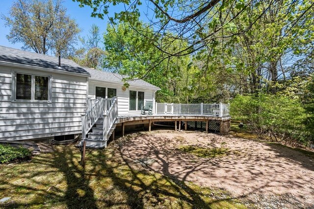 rear view of property with a deck and roof with shingles