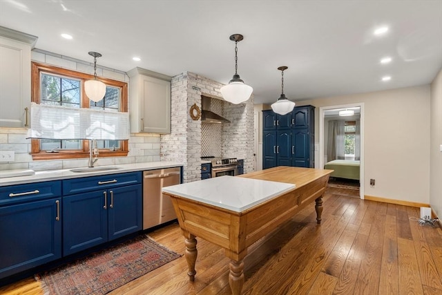 kitchen with light countertops, a sink, blue cabinetry, backsplash, and stainless steel appliances