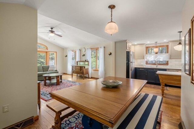 dining area featuring a ceiling fan, plenty of natural light, light wood-style flooring, and lofted ceiling